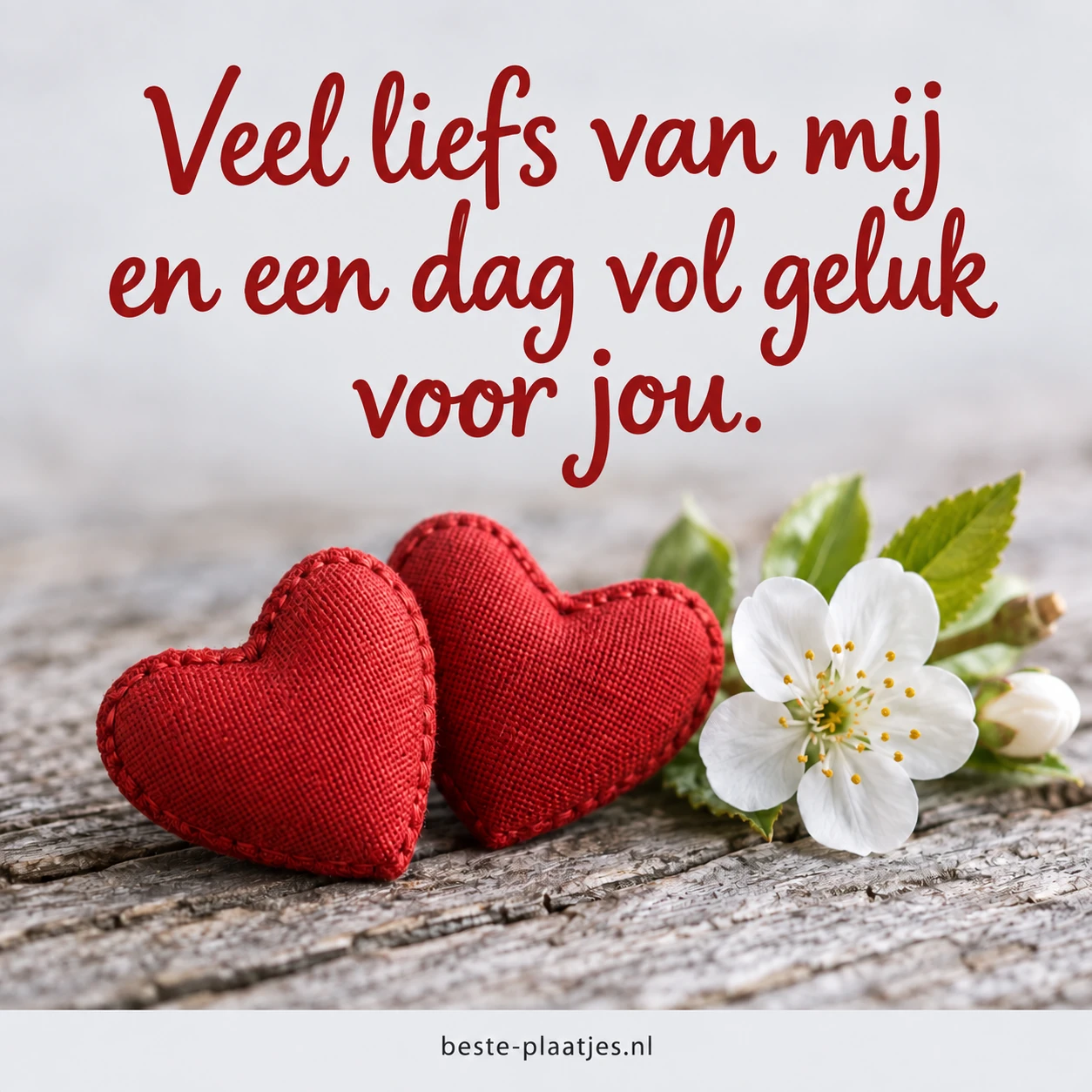 Twee rode harten en een witte bloesem op een houten tafel.
