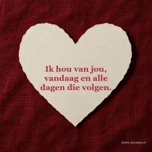 Een wit papieren hart ligt midden op dieprode geweven stof.