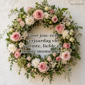 Een krans van rozen en witte bloemen hangt tegen een lichte muur.