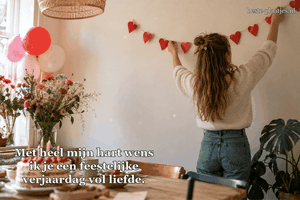 Een meisje hangt een slinger van rode papieren hartjes op.