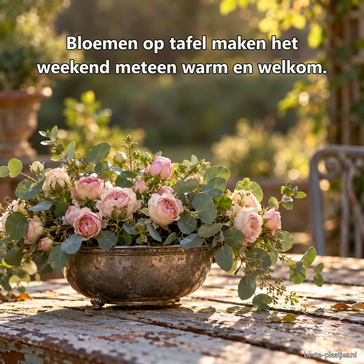Een oude tinnen schaal met roze rozen staat op een tuintafel.